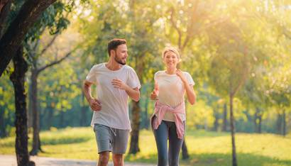 Portrait of Young couple running in the park at sunset. Concept sport and love. Warm tone.