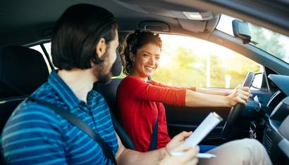 Jeune femme apprenant à conduire une voiture avec son instructeur.