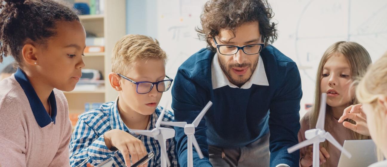 Teacher and pupils working at desk together