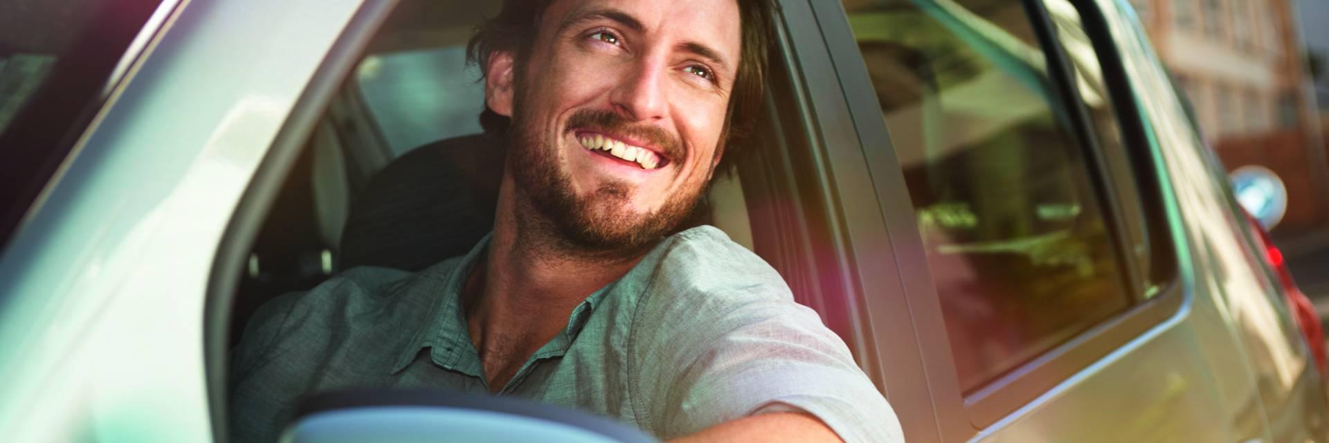 Homme souriant dans sa voiture a effectué un devis assurance auto