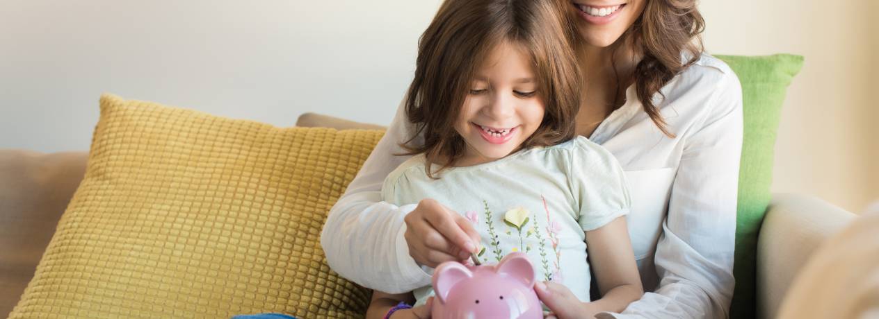 Petite fille et sa mère déposent de l'argent dans une tirelire en forme de cochon