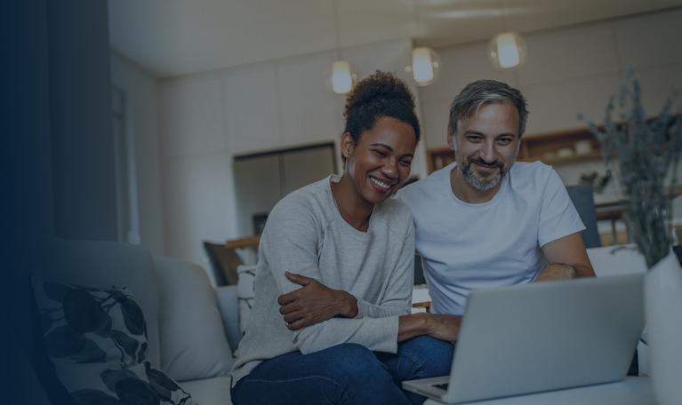 Couple souriant devant un ordinateur dans leur domicile