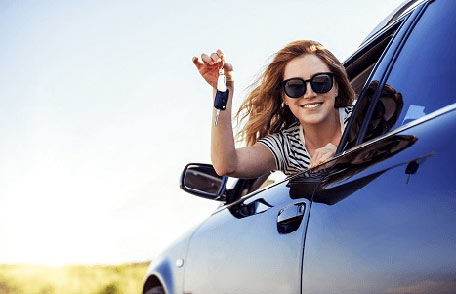Jeune femme à la fenêtre de sa voiture avec les clés à la main