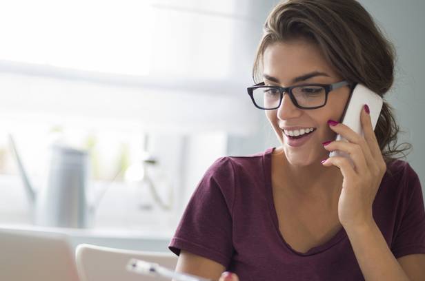 Femme appelle son assureur par téléphone et consulte son ordinateur pour en savoir plus sur la franchise auto