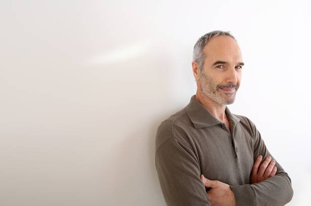 Portrait of 50-year-old man standing on white background